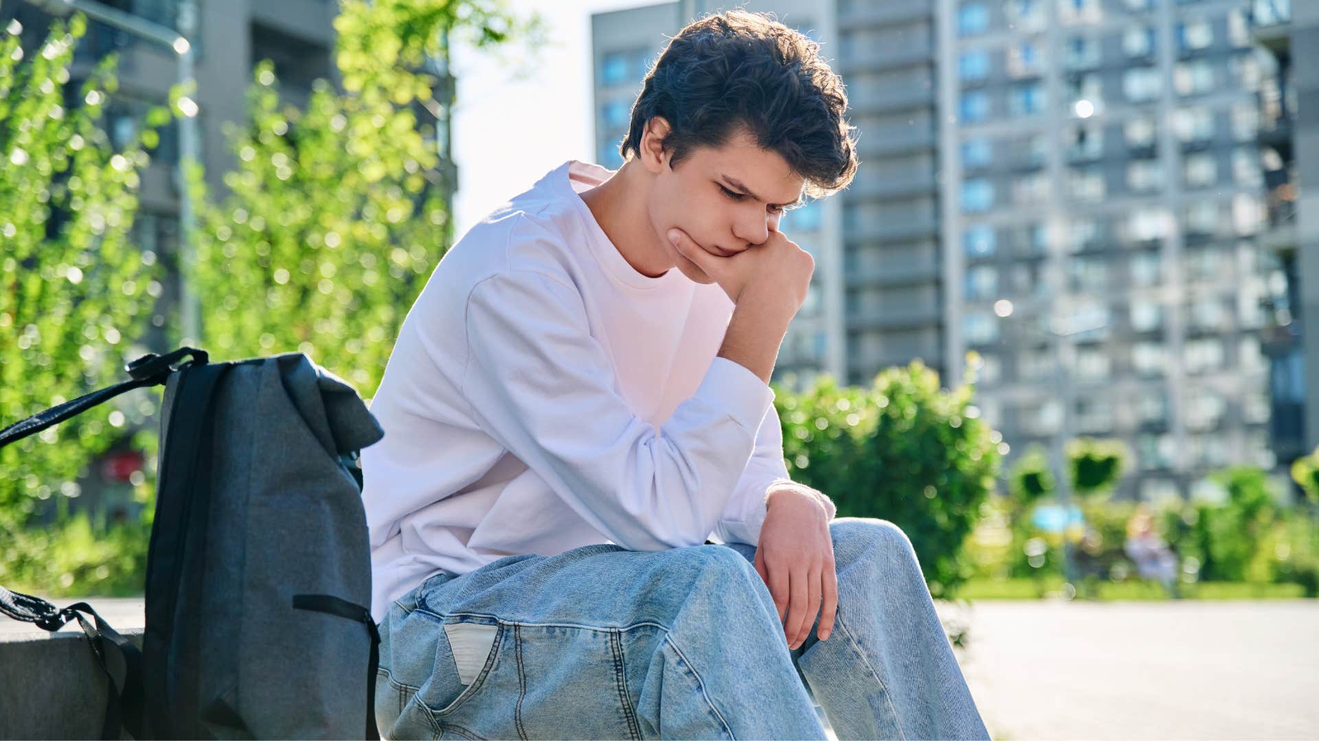 young man experiencing grief sitting outside alone