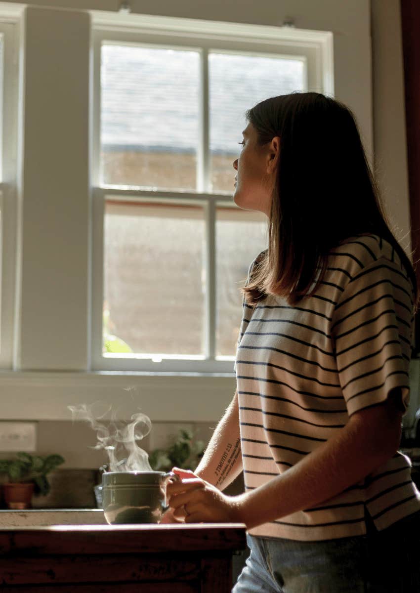 thoughtful stressed woman standing in home kitchen