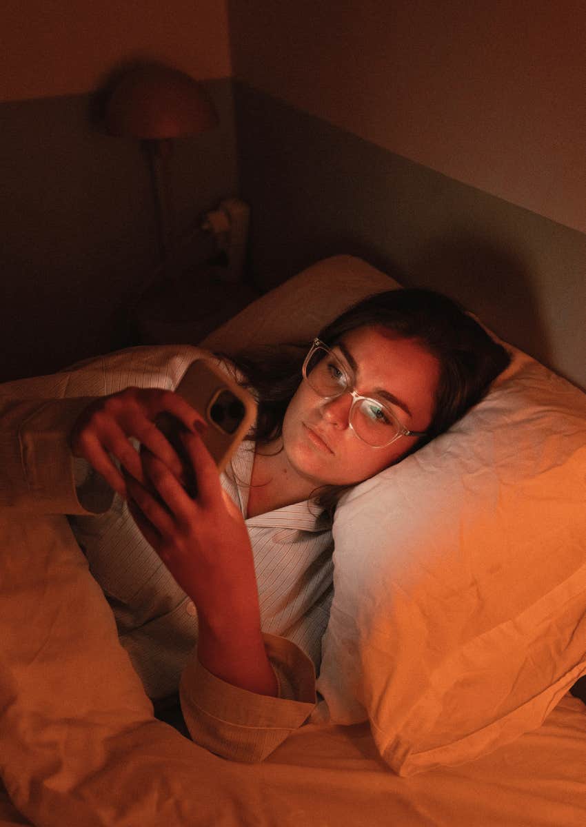 teenage girl in bed scrolling through her phone at night