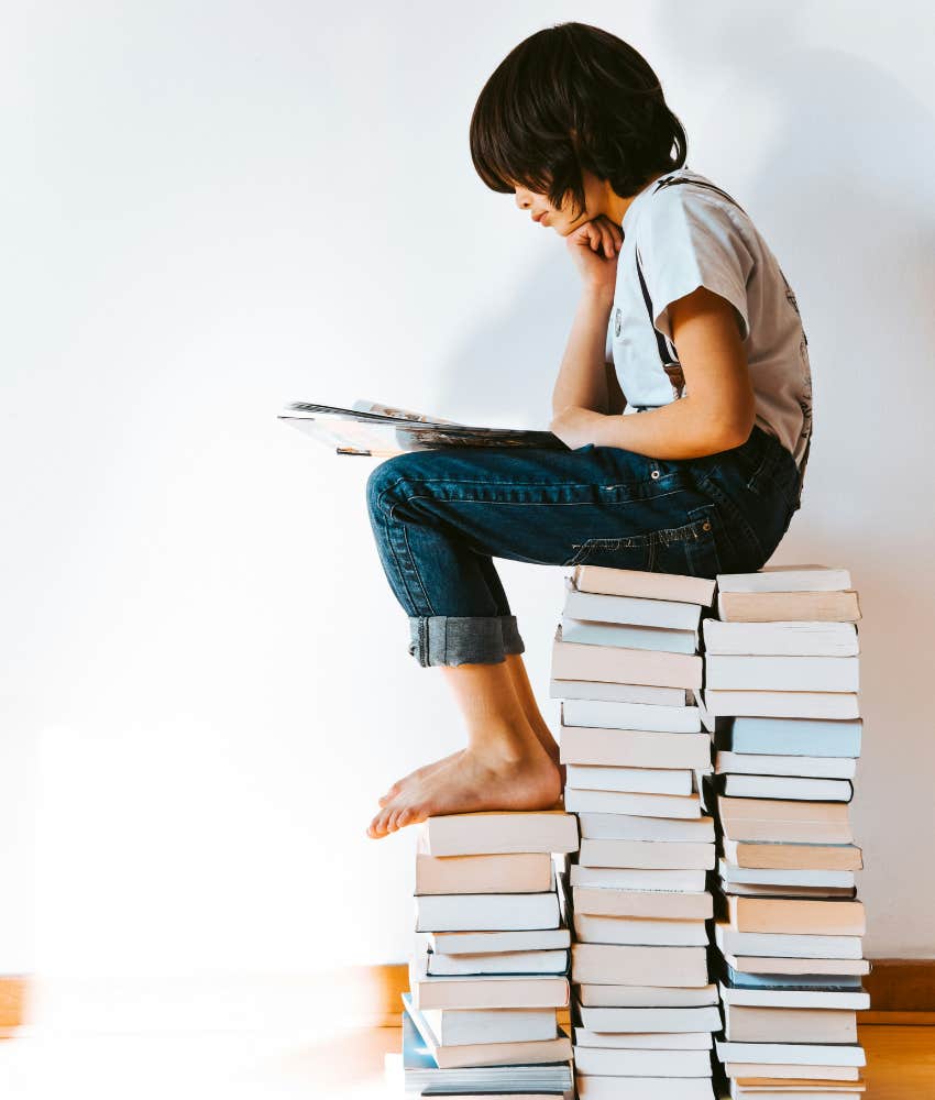 kids reads shile sitting on stack of books