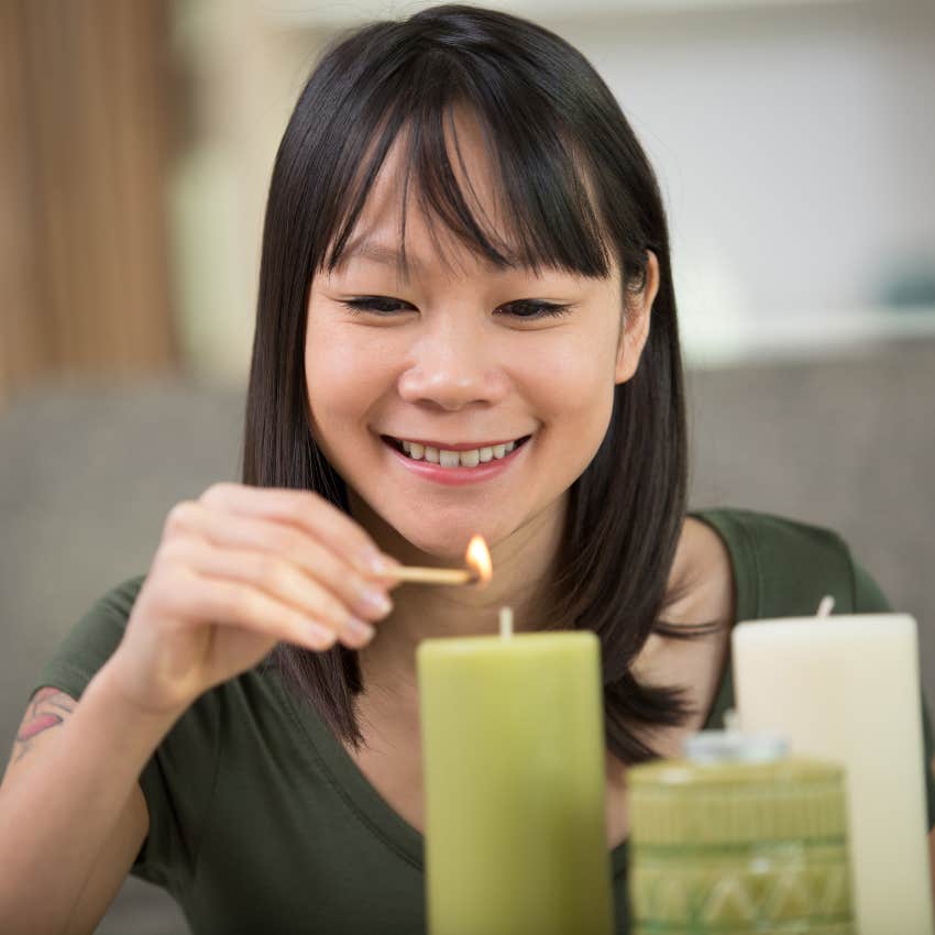 woman lighting green candle on the first of the month for luck and abundance