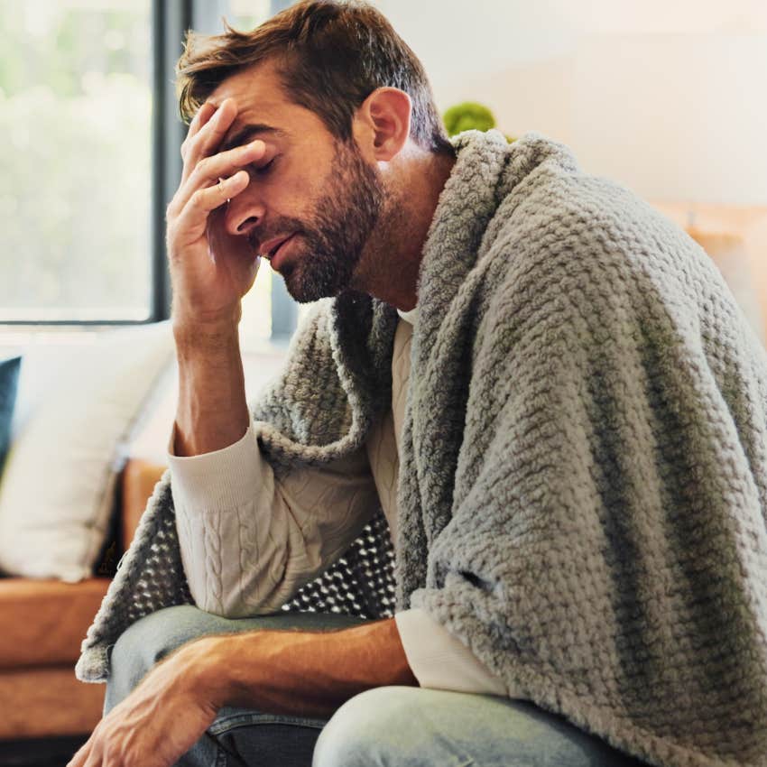 man who's physically drained sitting alone at home