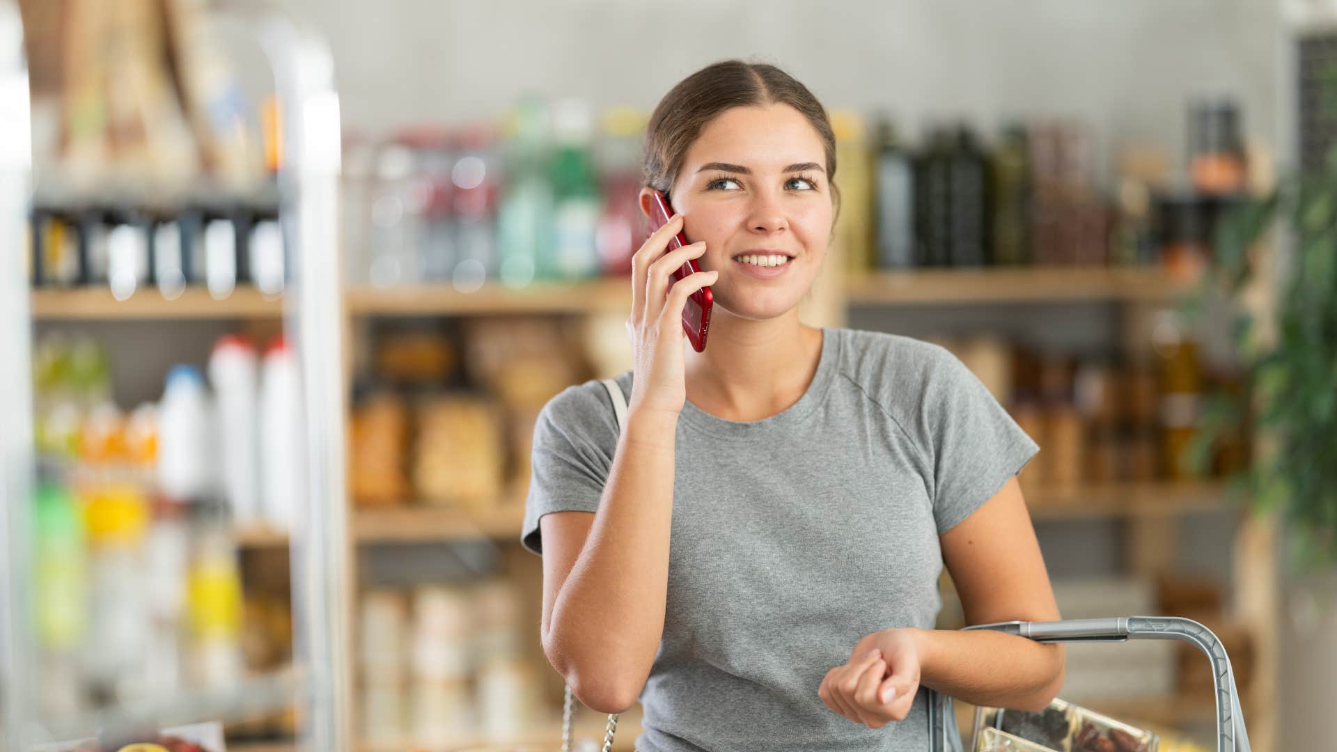 woman at the grocery store shopping while on the phone