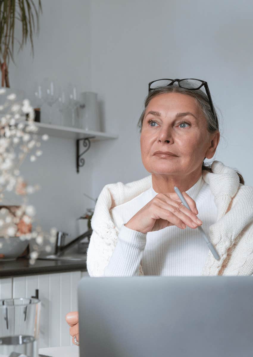 thoughtful middle aged woman with an open laptop