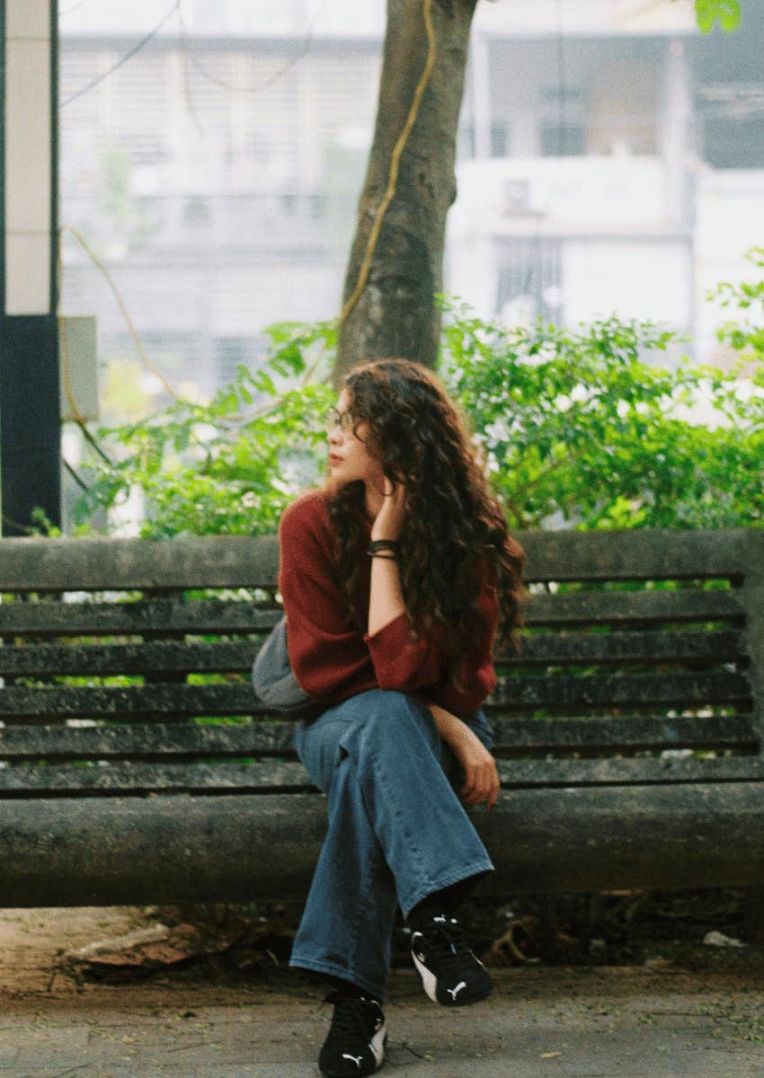 thoughtful woman sitting on park bench