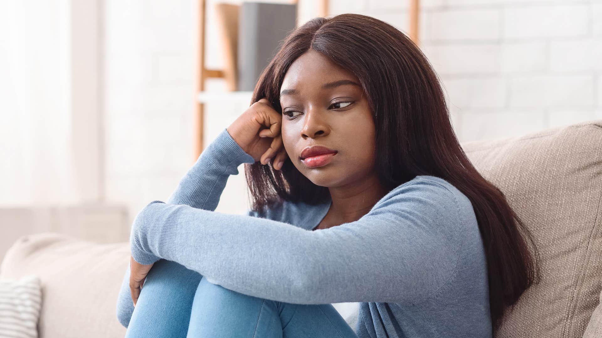 woman in blue shirt reflecting on couch as she realizes Most arguments matter far less than they felt at the time