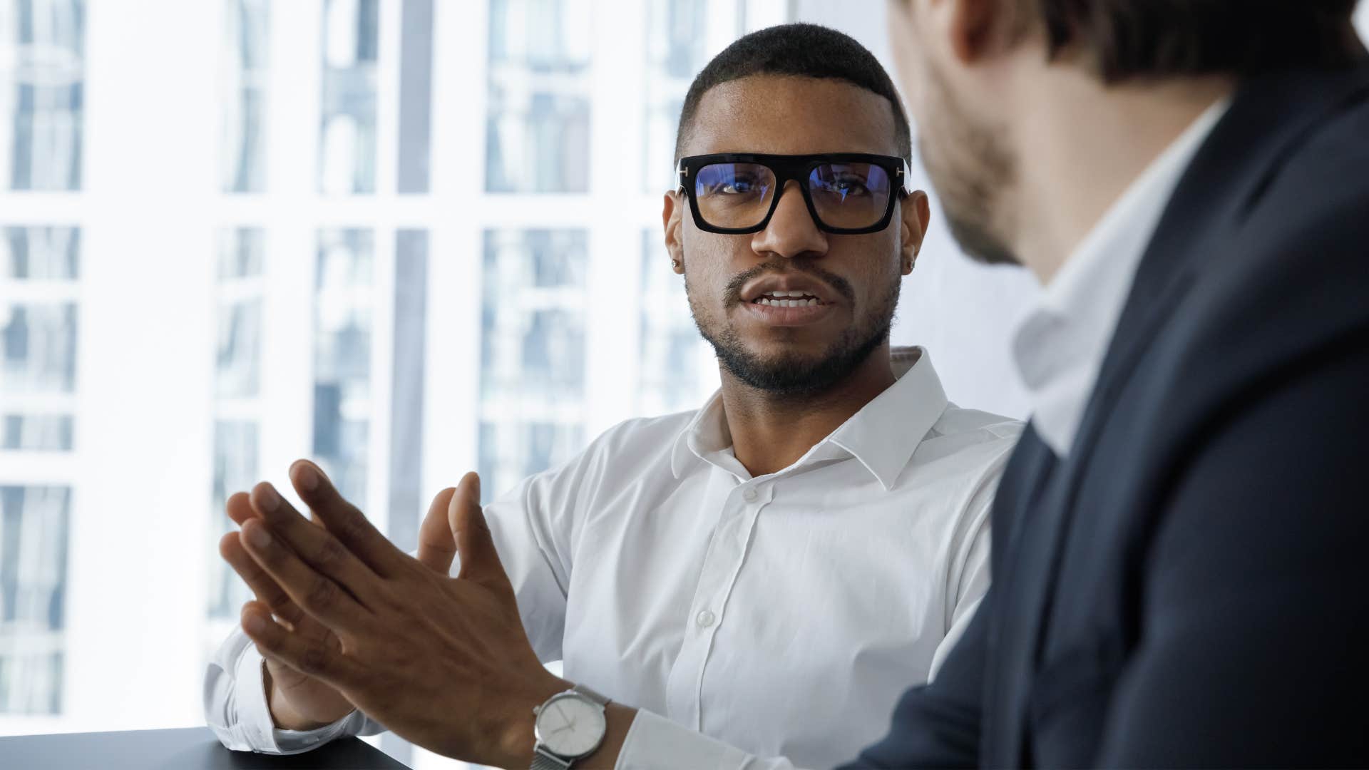 Man talking to an oversharing co-worker in an office.