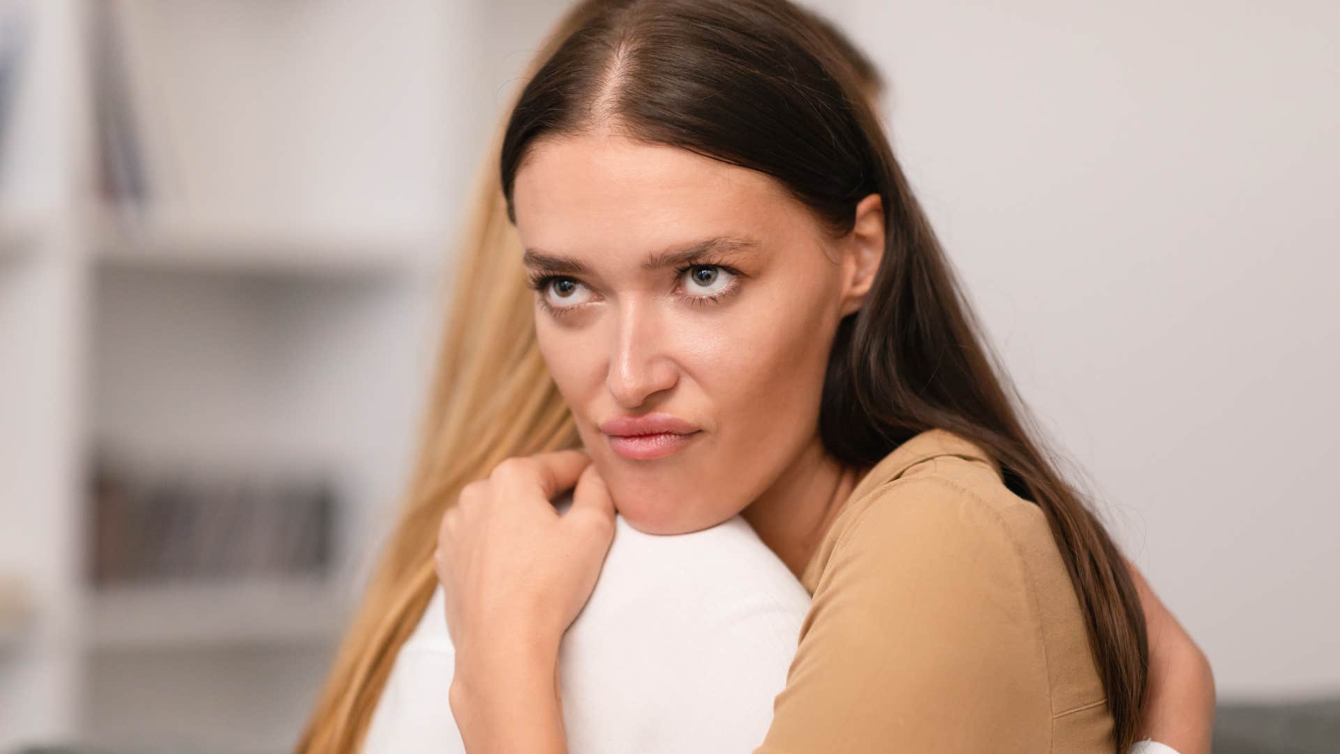 narcissistic woman rolling her eyes while hugging a friend