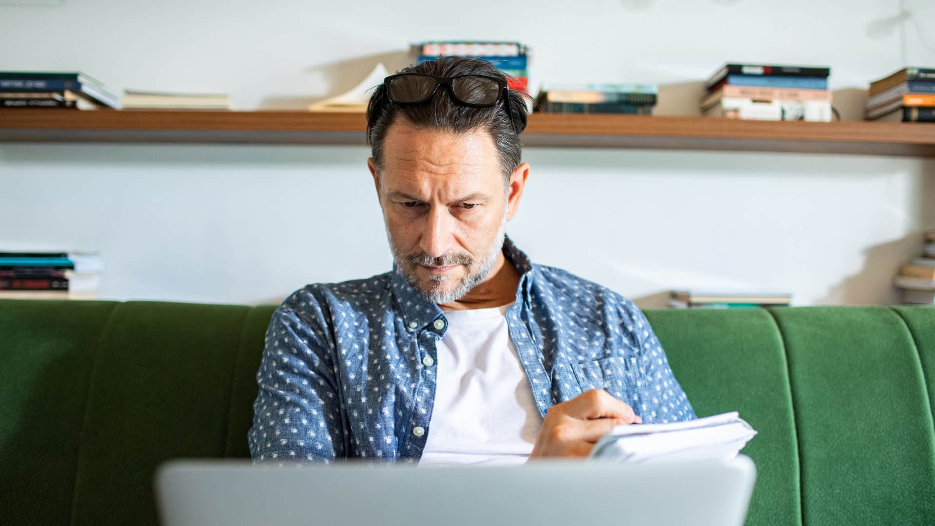 man taking notes in casual conversations on laptop while sitting on green couch
