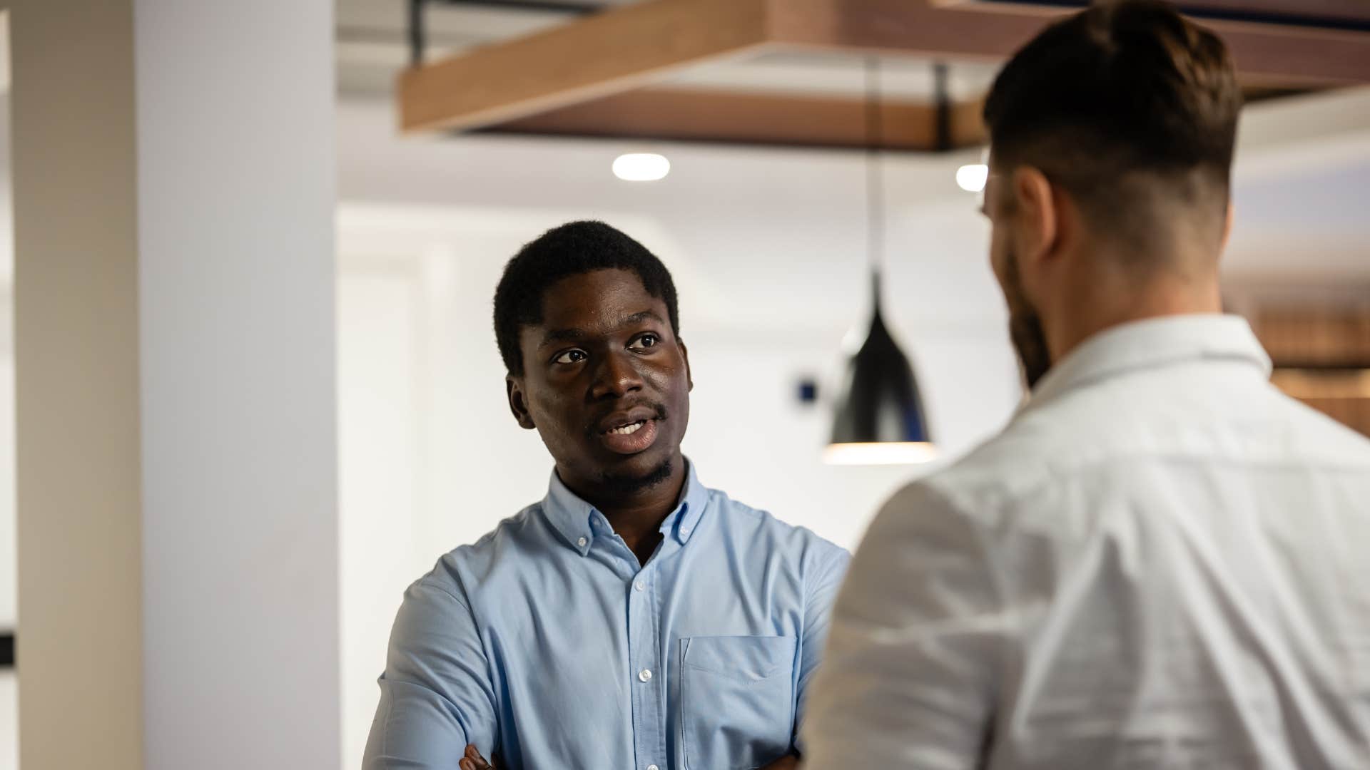 coworkers talking as man in blue shirt is about to walk away from conversation early