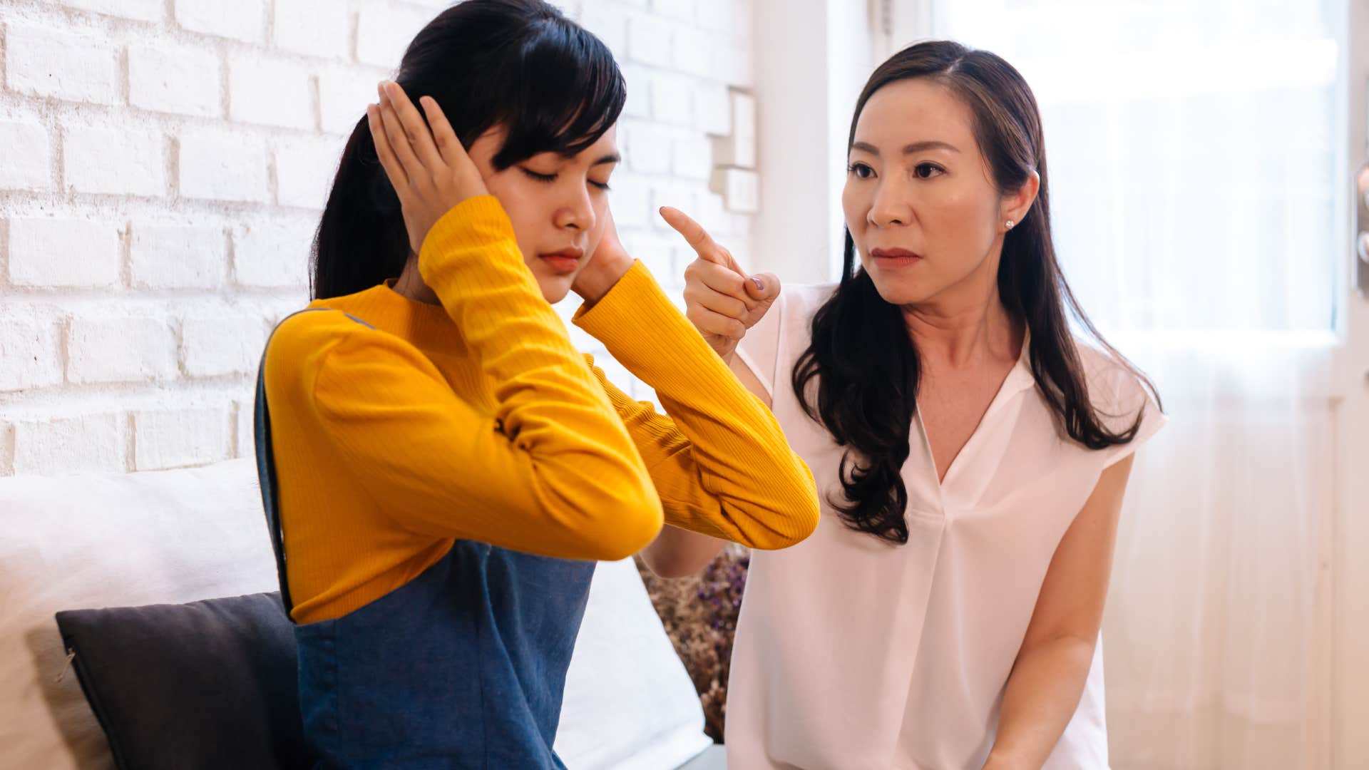 adult daughter covering her ears to her mom's narcissistic tendencies
