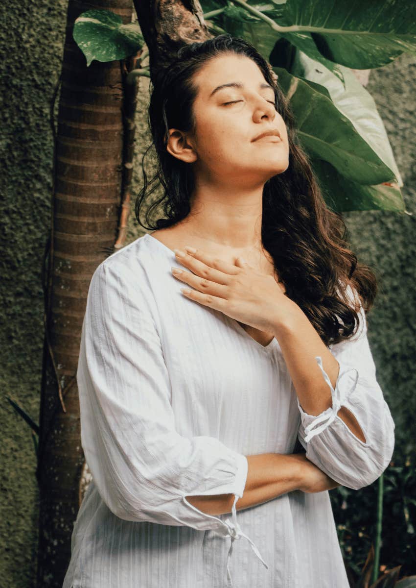 woman with her hand on her chest breathing in deeply