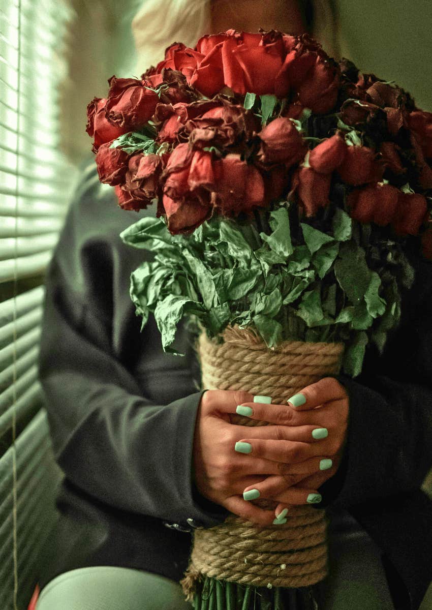 woman holding a bouquet of wilted roses