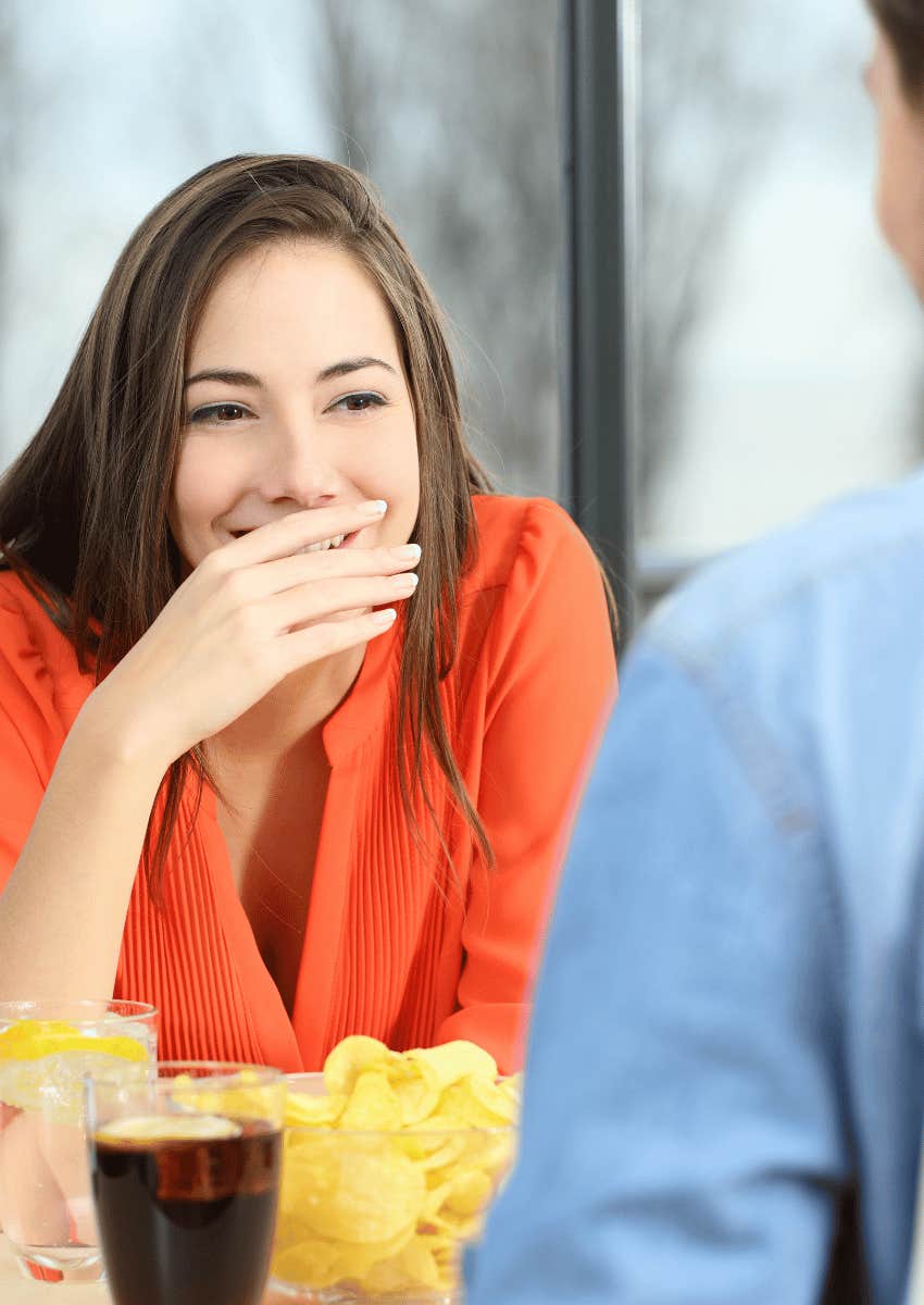 woman shyly laughing across from man