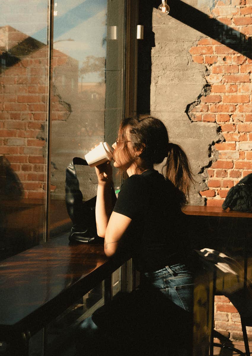 woman sitting alone at cafe with lowered expectations
