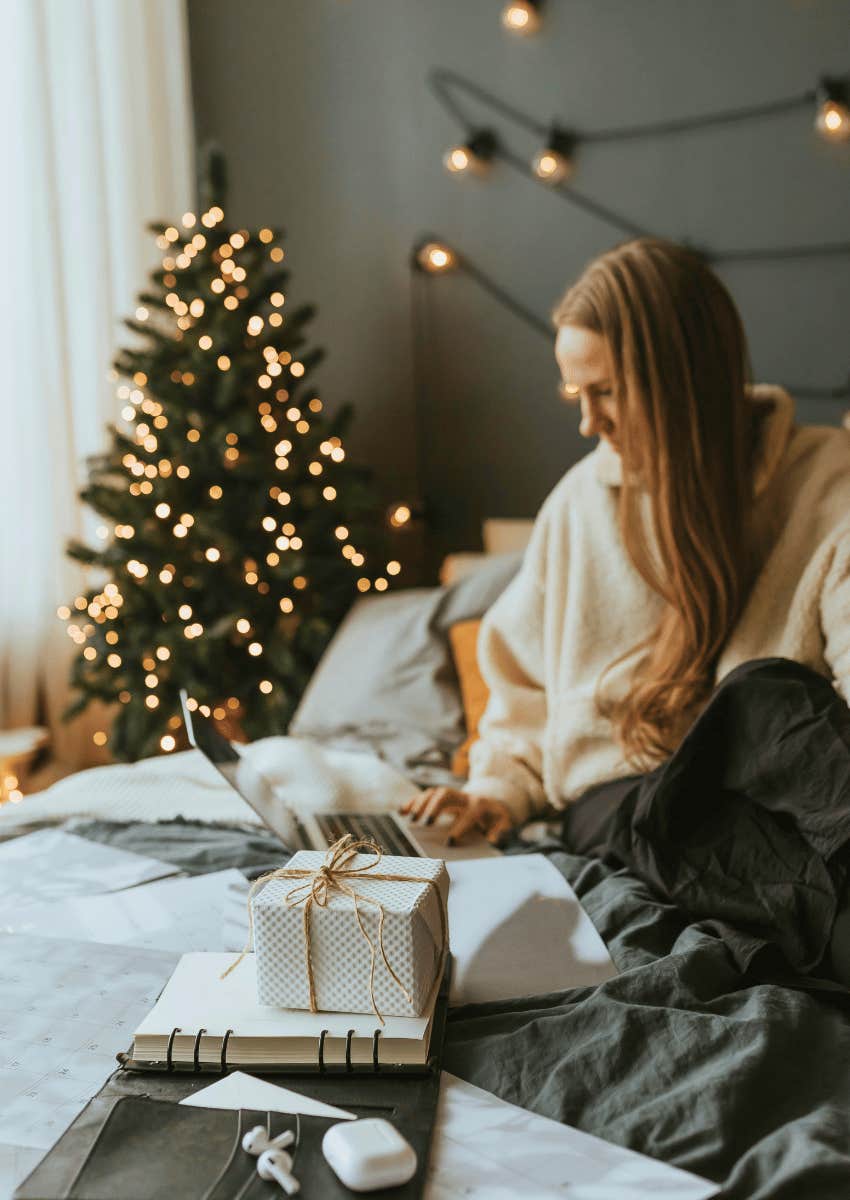 woman working on her bed with a christmas tree in the background