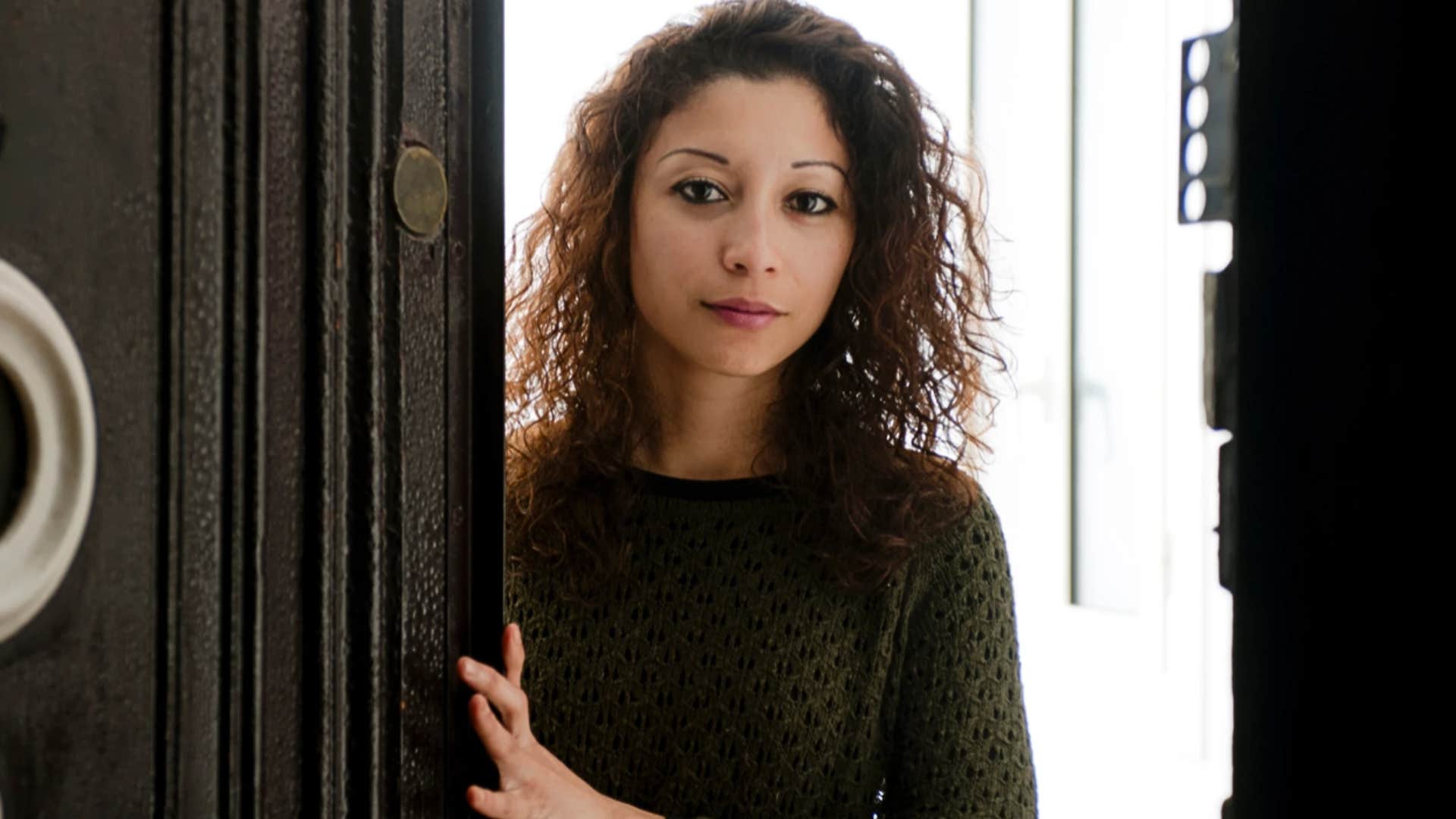 Woman who was the eldest daughter standing by a window looking cautious