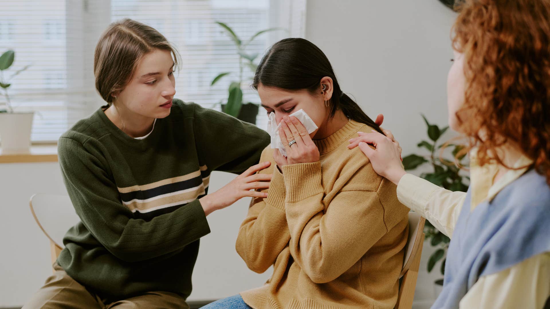 woman crying while her friends comfort her