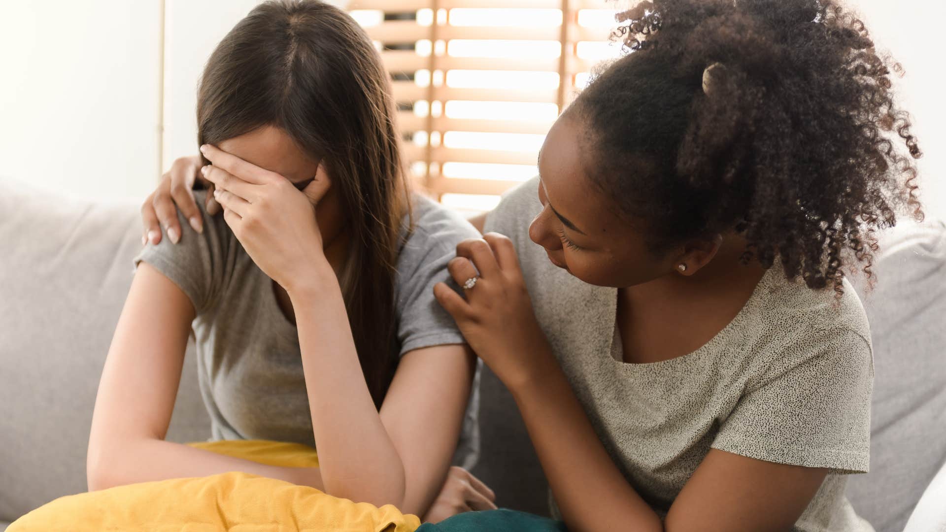 woman feeling waves of deep sadness while friend comforts her