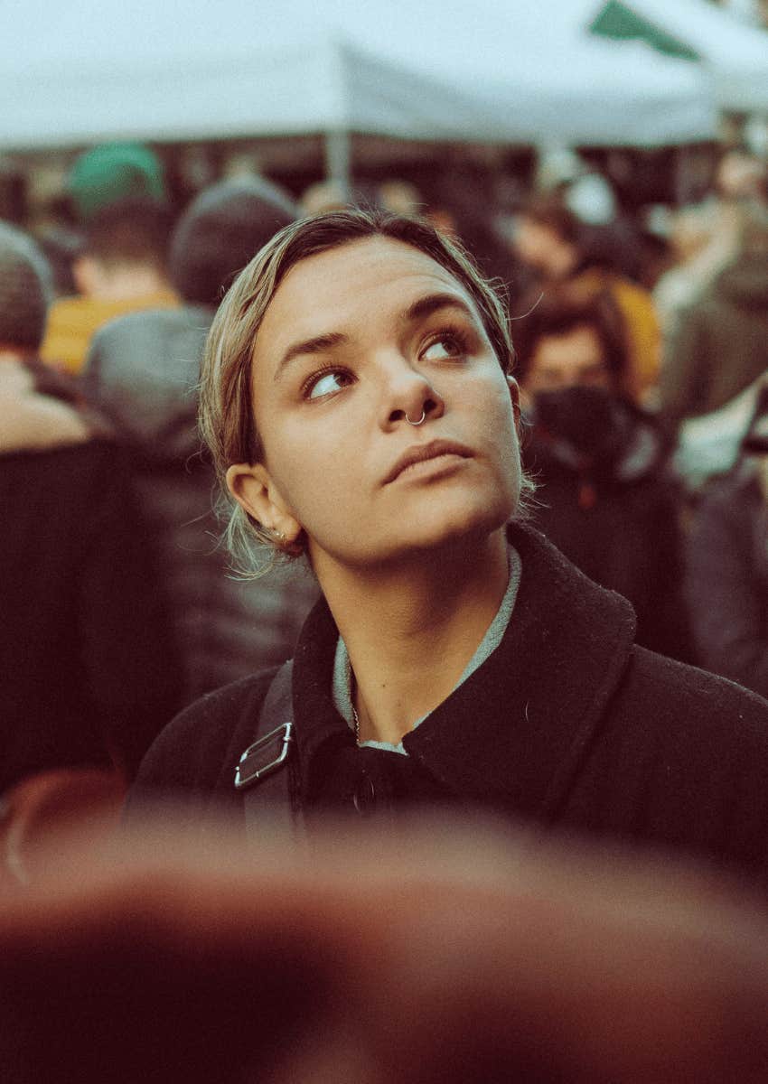 young adult woman standing alone in a crowd