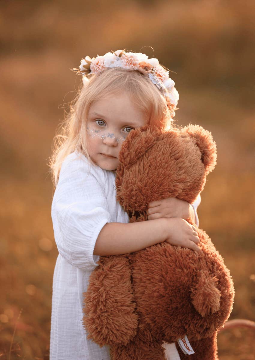 young girl hugging her stuffed animal close