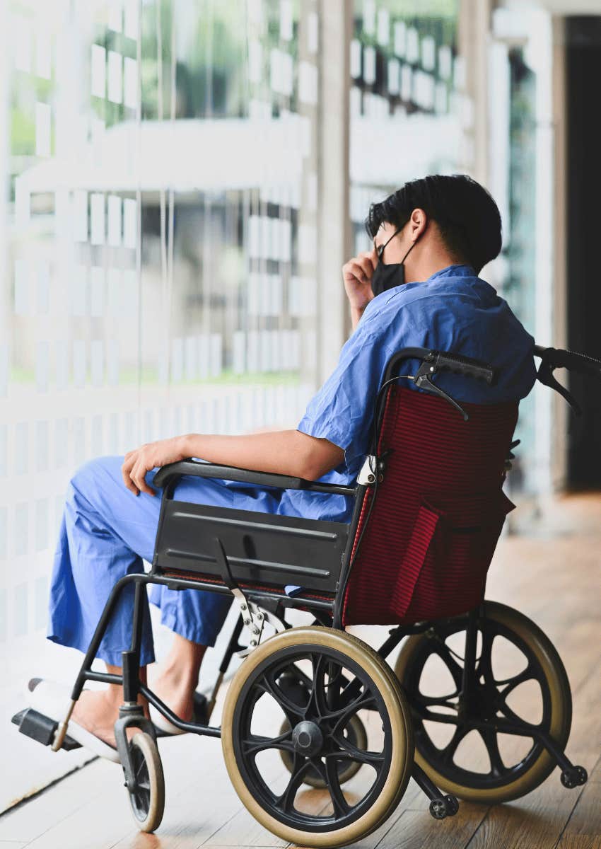 young man in wheelchair looking out of window thoughtfully