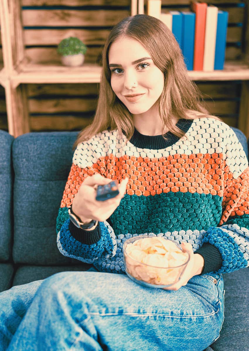 young woman holding a bowl of chip watching a movie at home
