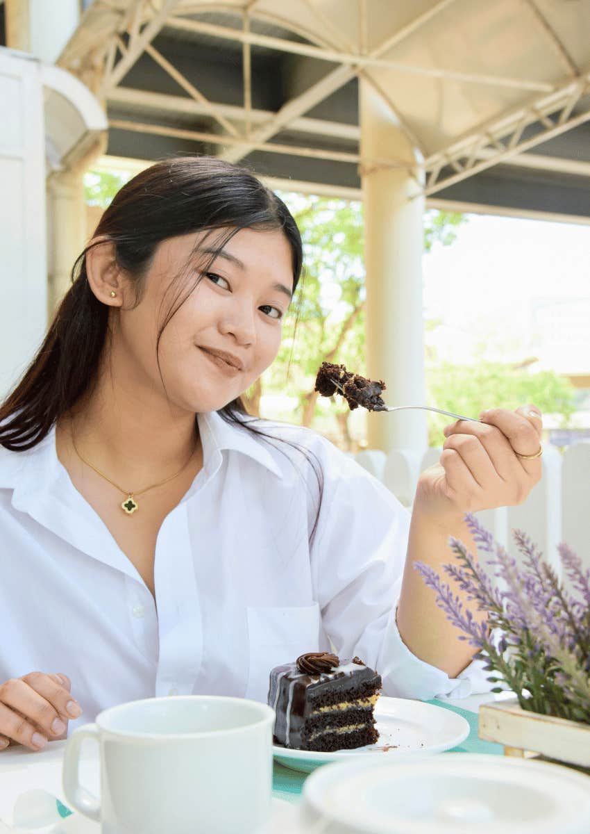 young woman raising piece of chocolate cake