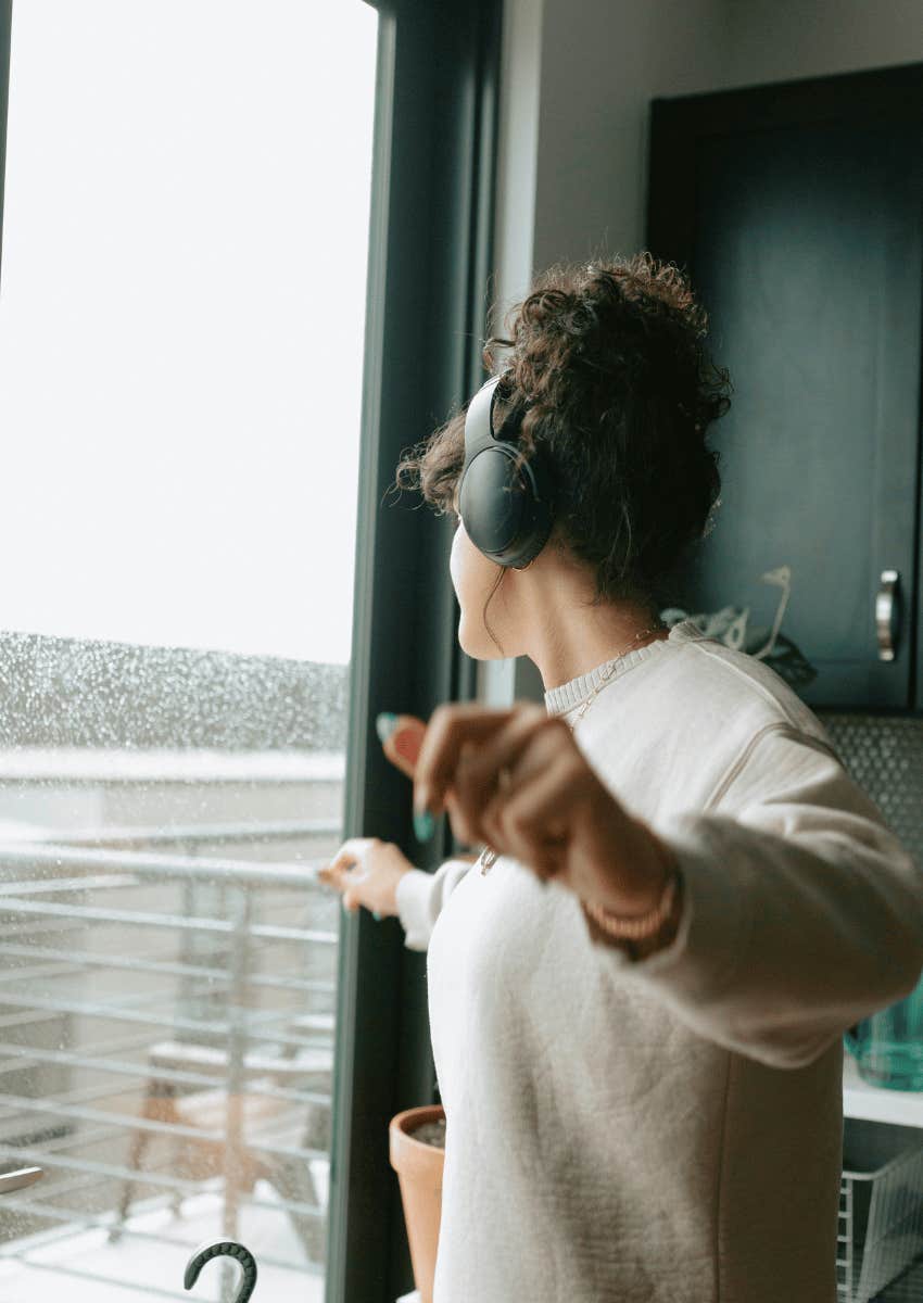 young woman with headphones dancing in the kitchen