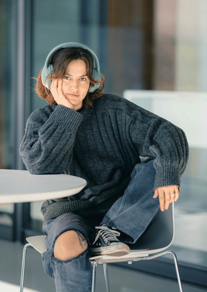 young woman sitting at an outdoor table listening to music