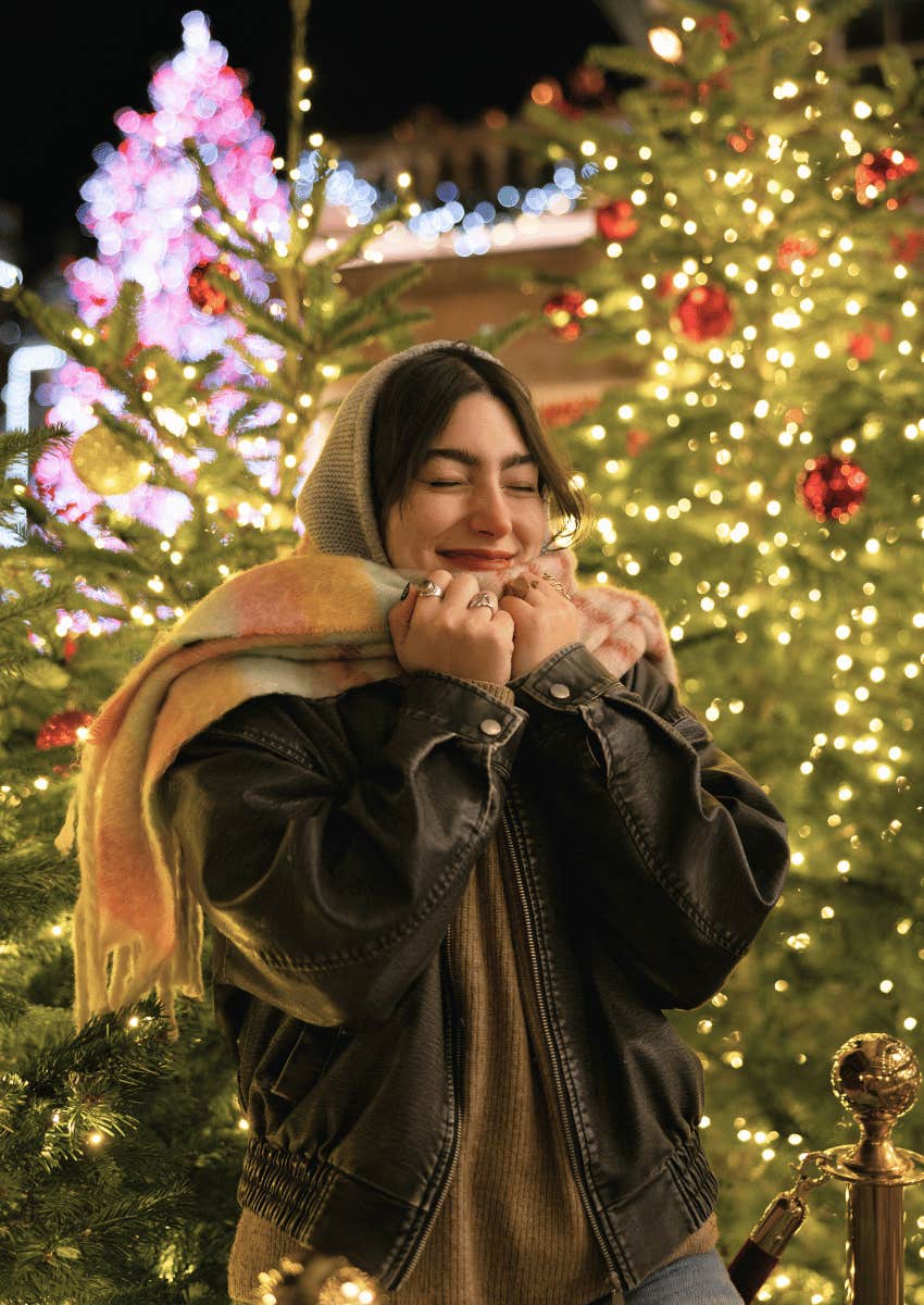 young woman smiling in front of christmas tree lights