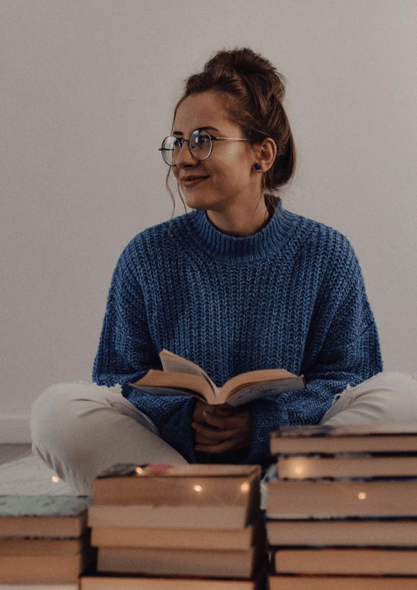 young woman surrounded by a stack of books