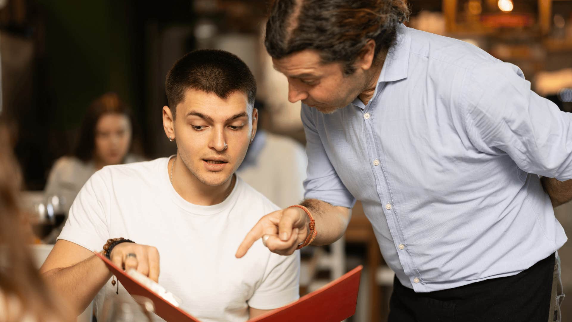 man looking at menu asking multiple servers for the same thing at a restaurant