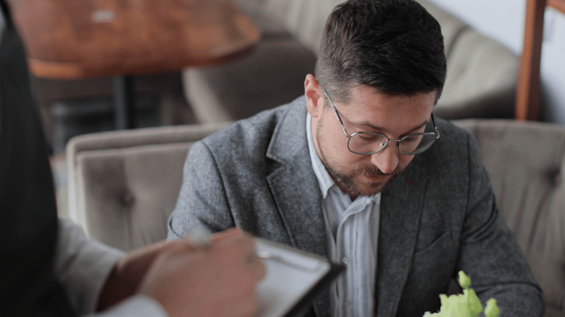 man not making eye contact with waiter taking his order