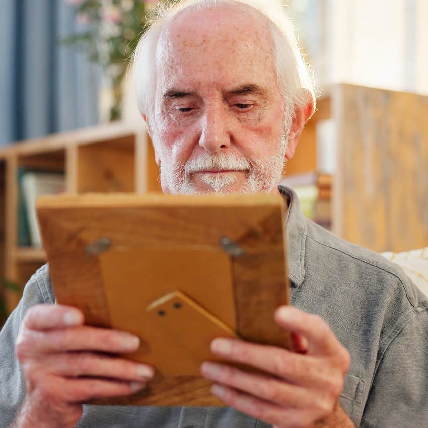 sad older man holding photo frame thinking about losing friends and family