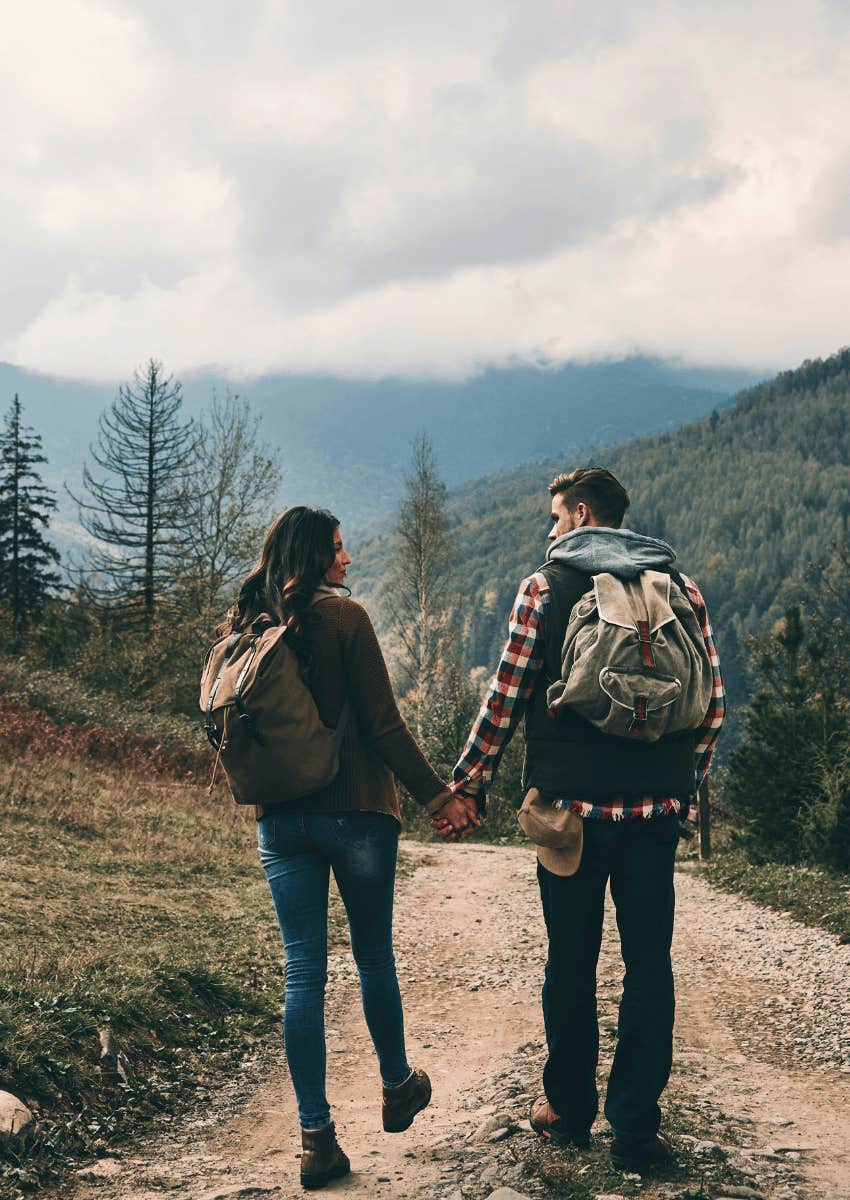 couple holding hands and slowly walking down path