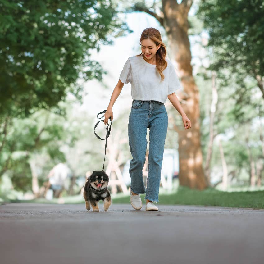 woman walking small dog in park