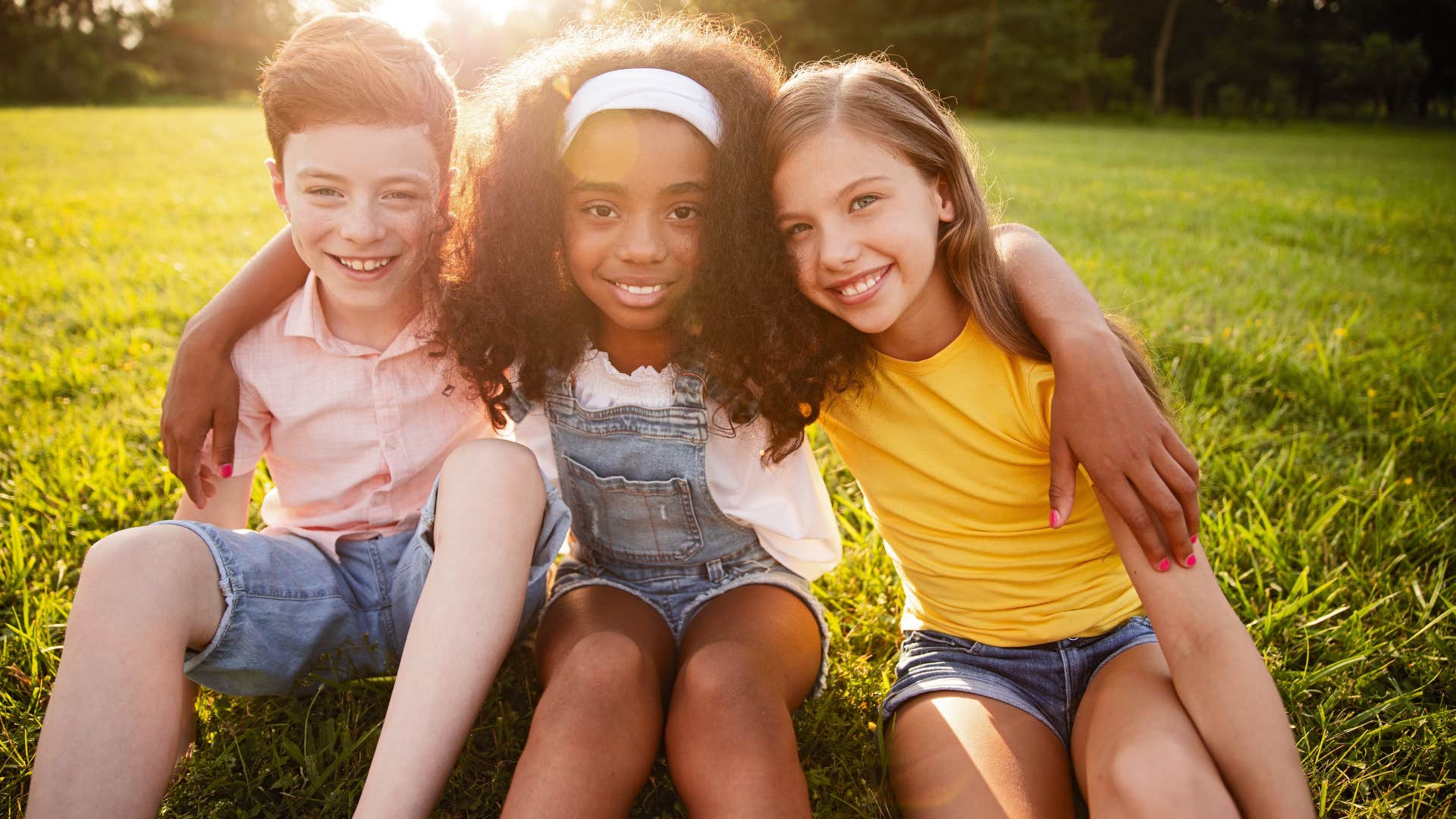 kids sitting in a field having a playdate smiling