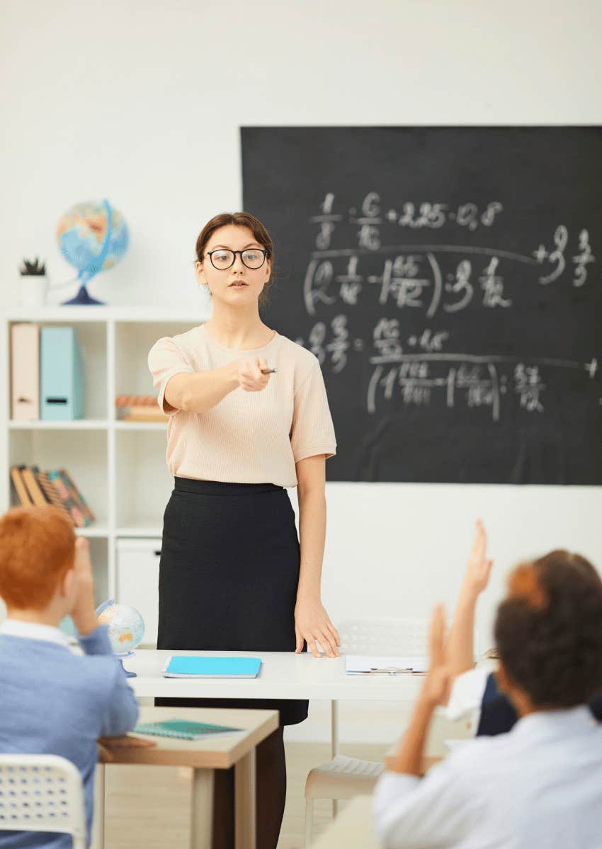female teacher calling on student with raised hand