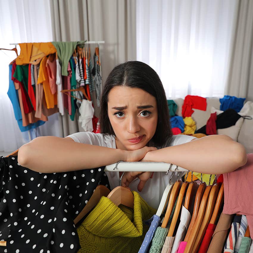 woman stressed in cluttered room of clothes