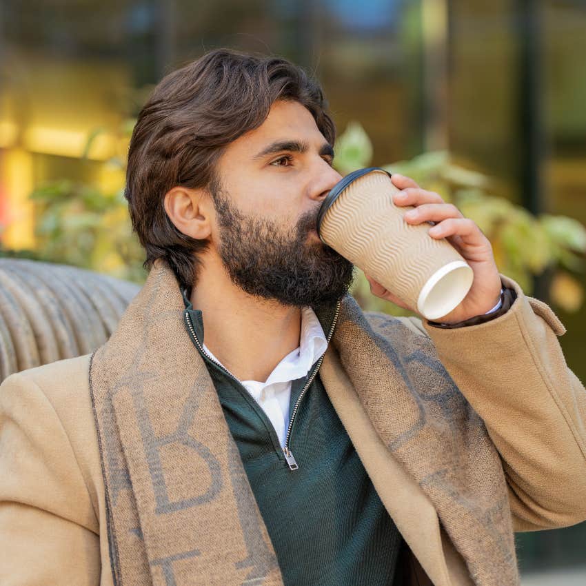 handsome man drinking out of takeout coffee cup outside