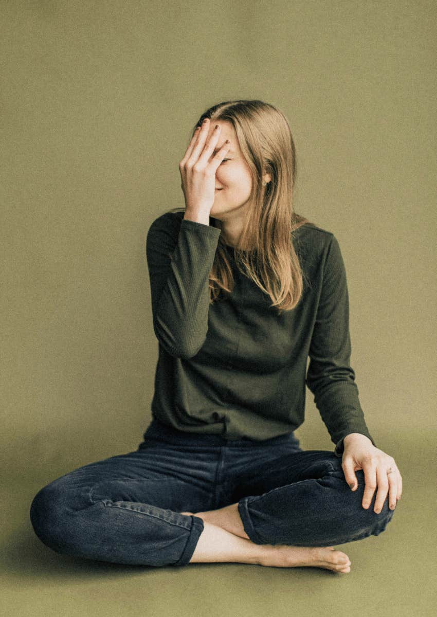 flustered young woman covering her face
