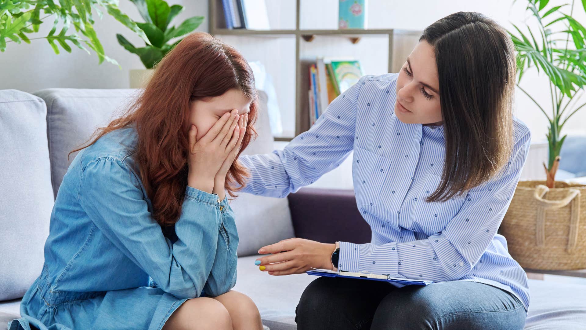 Mom tries to comfort her stressed and overworked Gen Z adult daughter on a couch