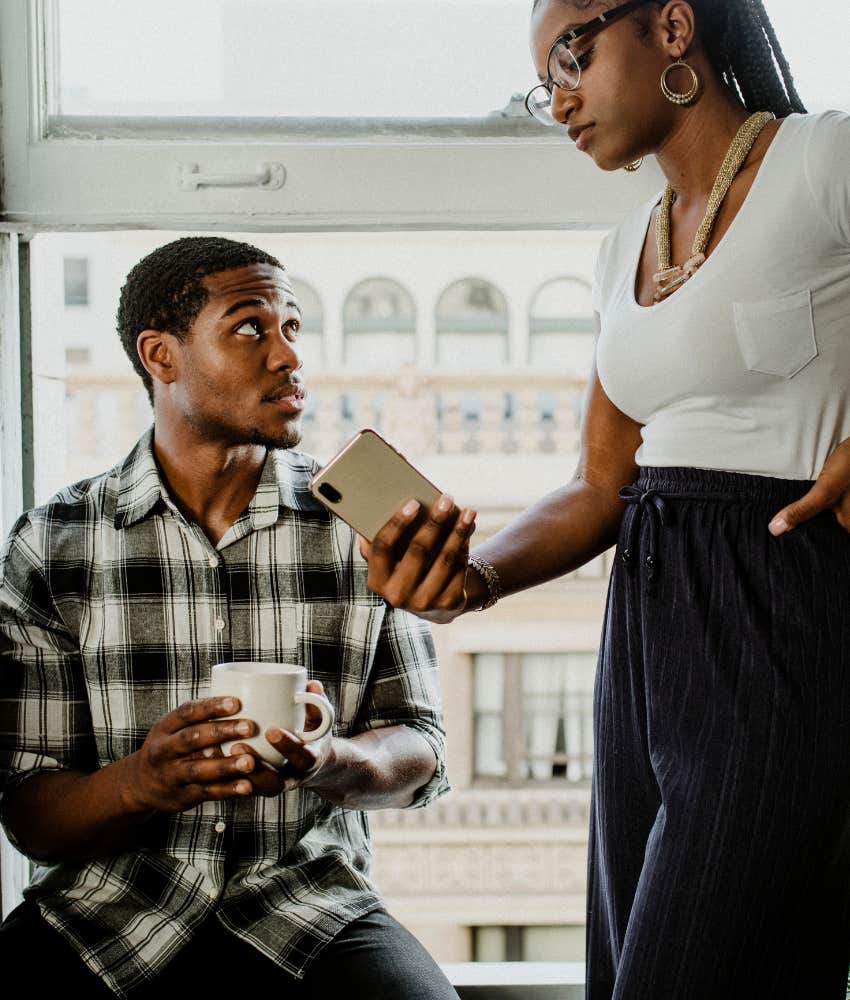 wife shows surprised husband mobile device showing defensivness