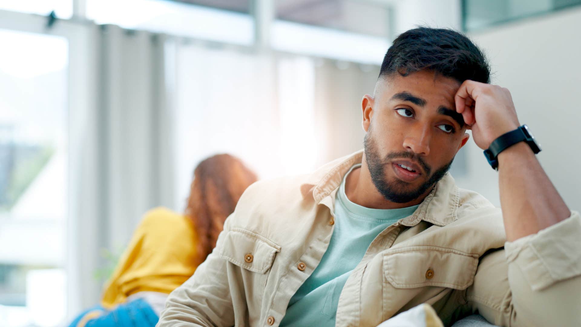 annoyed man sitting away from woman who keeps repeating herself