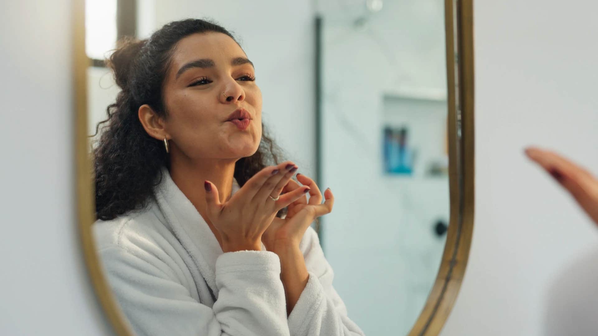 Woman who has wasted enough time smiles in the mirror at herself
