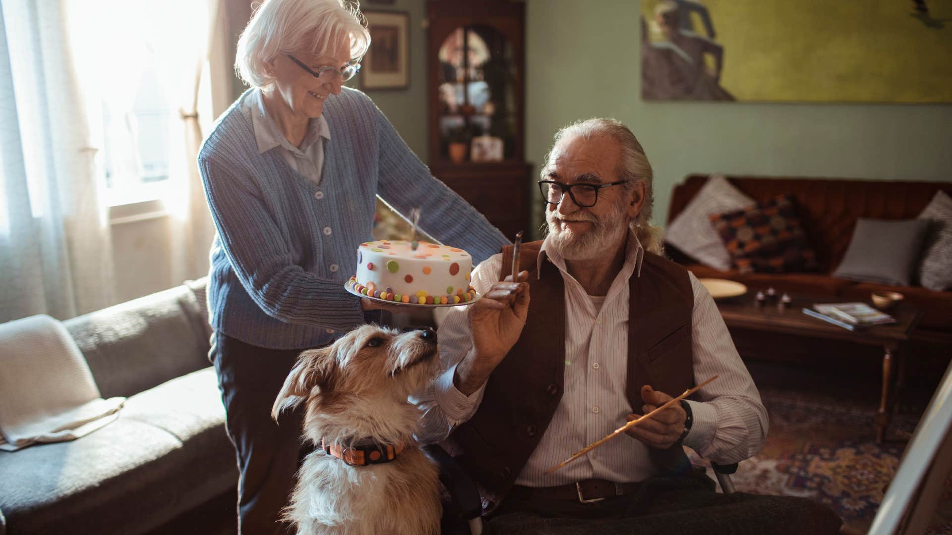 older couple holding cake to celebrate their dog's birthday