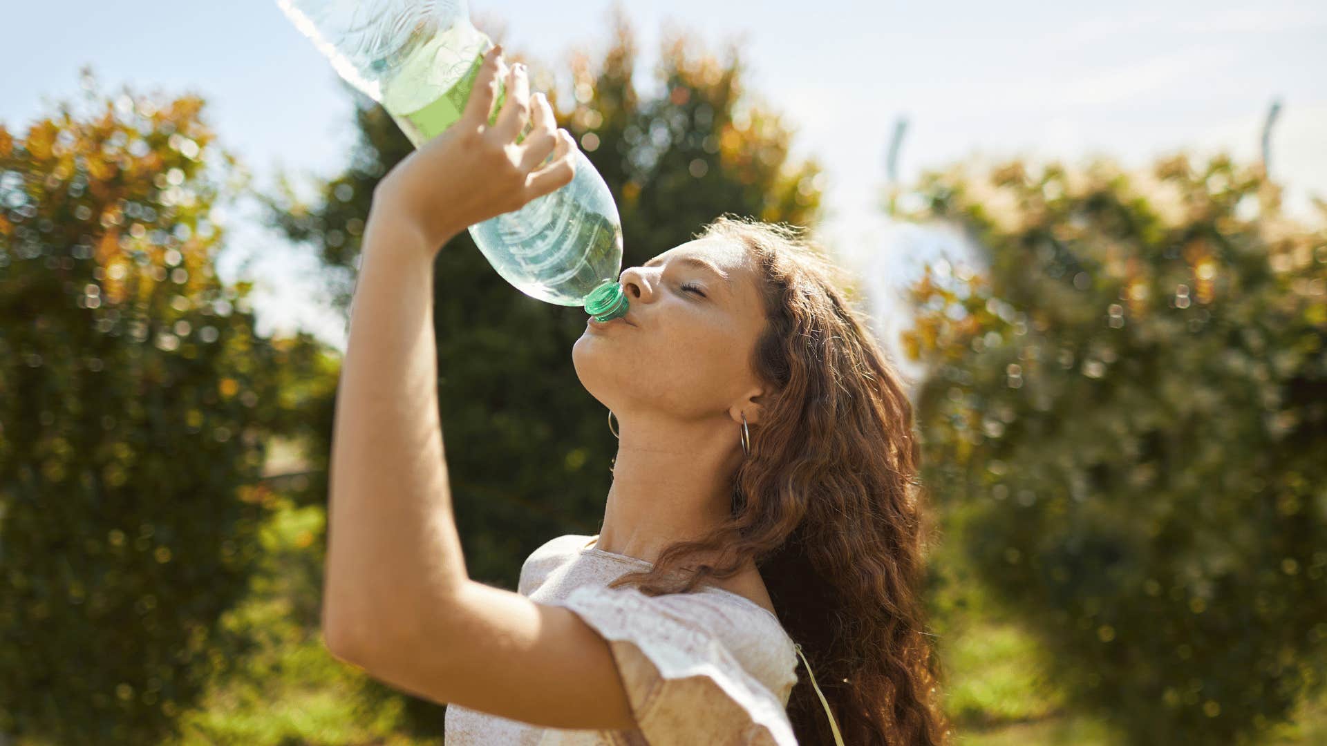 woman with zero dollars drinking bottled water