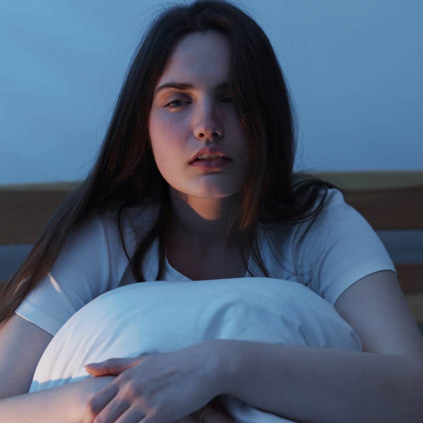 woman sitting up in bed unable to sleep next to her partner