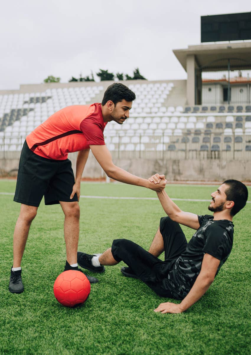 kind young man trusting his gut to help friend up